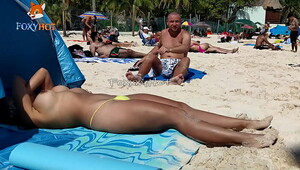 Sunbathing topless on the beach to be watched by other men